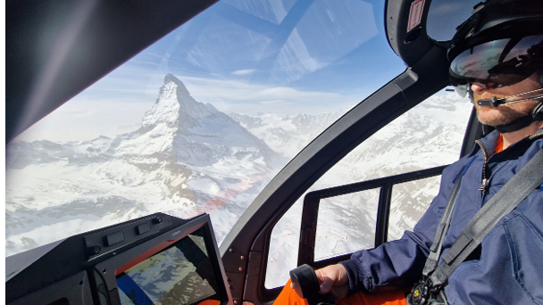 A man in a helicopter flying over a snowy mountain. Description generated by AI