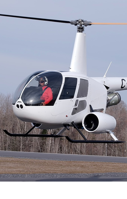 A man is in a helicopter flying over a field. Description generated by AI