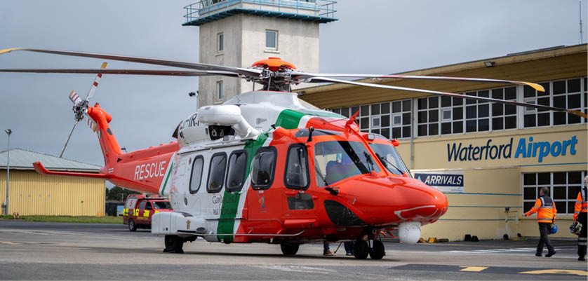 A red and white helicopter is parked in front of a building. Description generated by AI