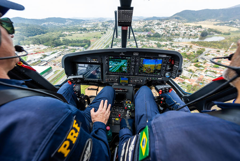 Two men in blue shirts are in a helicopter. Description generated by AI