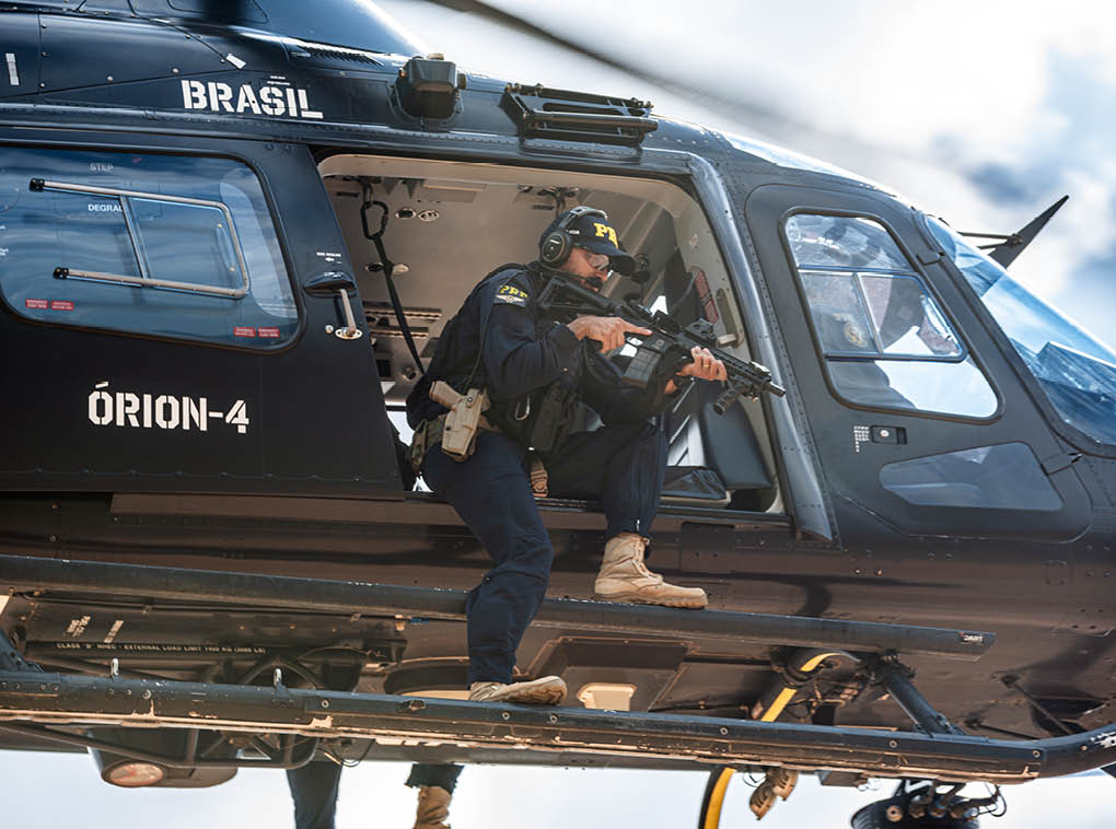 A man is standing in a helicopter with a gun. Description generated by AI