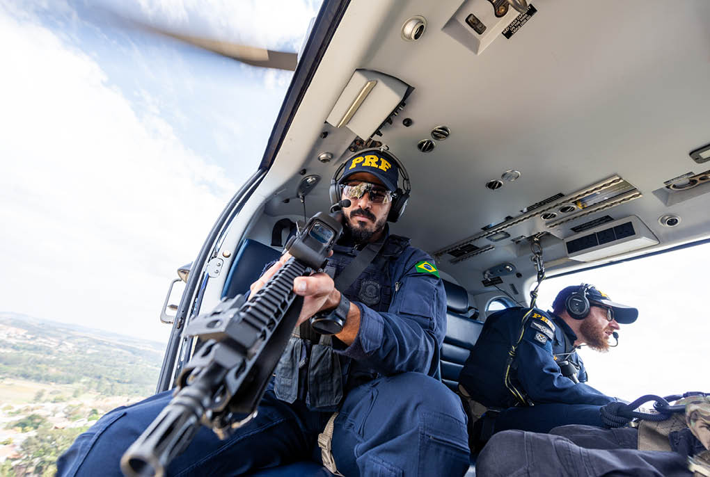 A man holding a gun in a helicopter. Description generated by AI