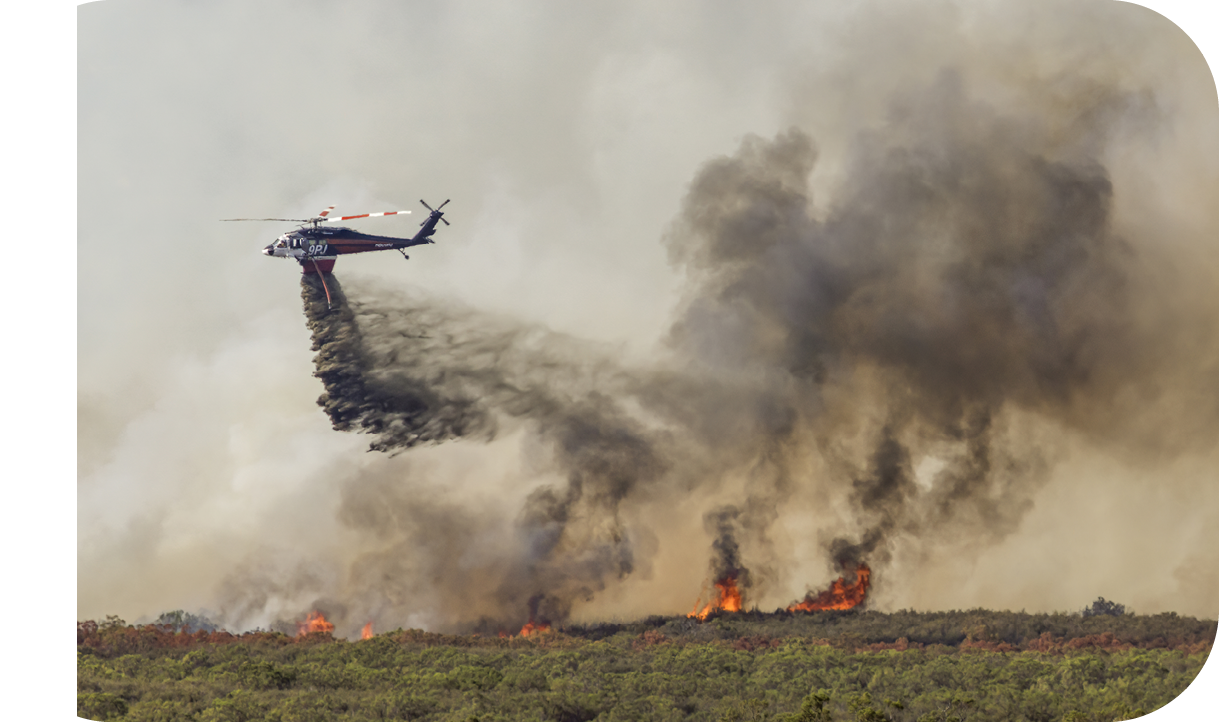 A helicopter is flying over a forest fire. Description generated by AI