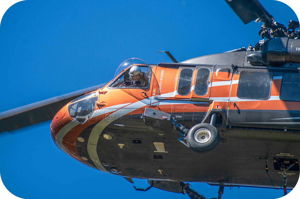 A helicopter with a man inside flying in the sky. Description generated by AI