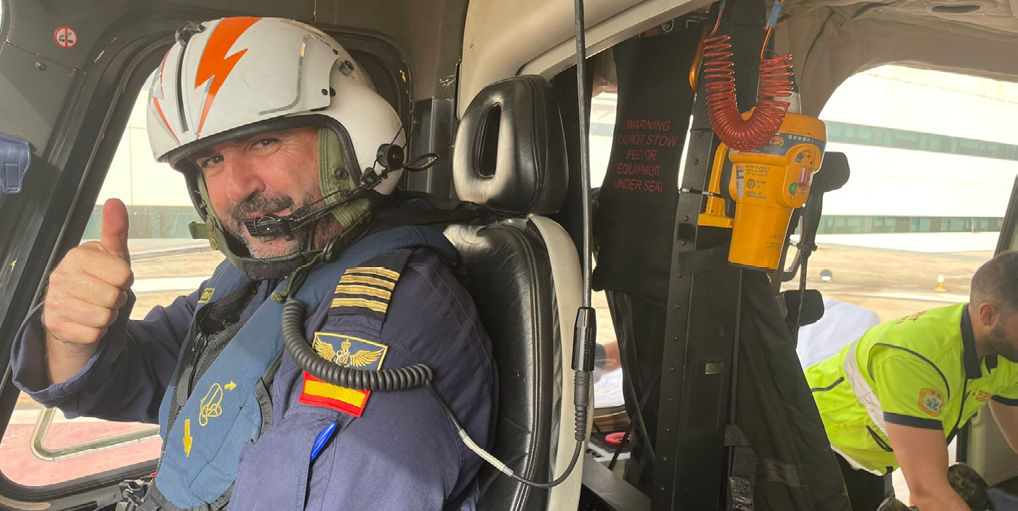 A man in a helicopter is giving a thumbs up. Description generated by AI