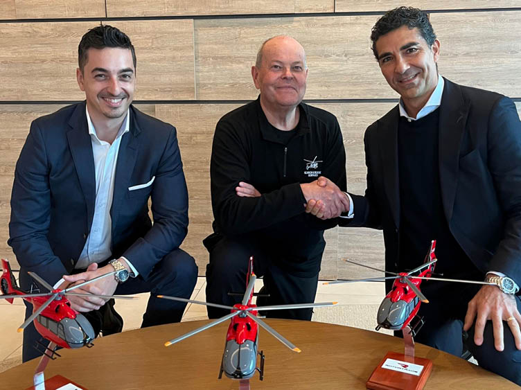 Three men are sitting around a table with toy helicopters. Description generated by AI