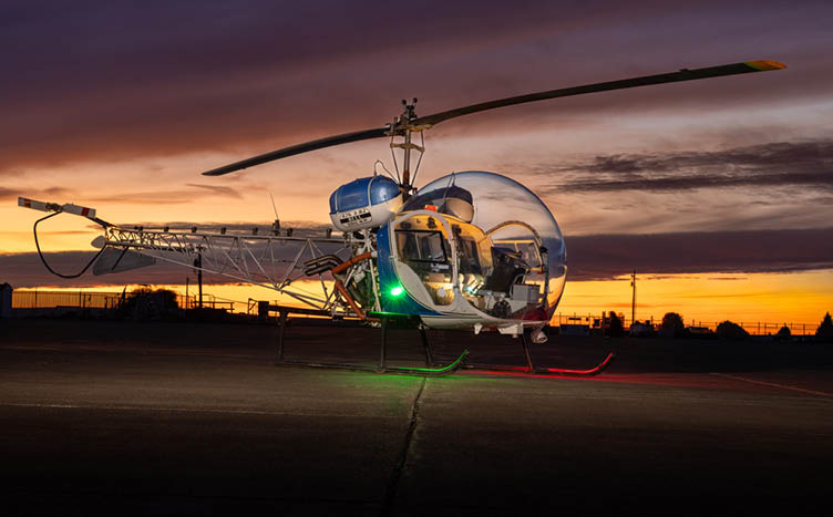 A helicopter with a green light on the bottom. Description generated by AI