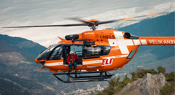 A helicopter with a man in a red jacket on it. Description generated by AI