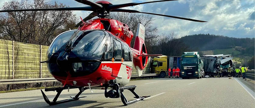 A red and white helicopter is parked on the side of a road. Description generated by AI