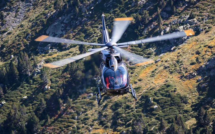A helicopter flying above a mountain. Description generated by AI