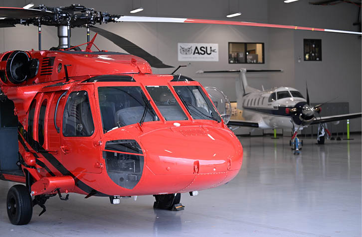 A red helicopter is parked in a hangar. Description generated by AI