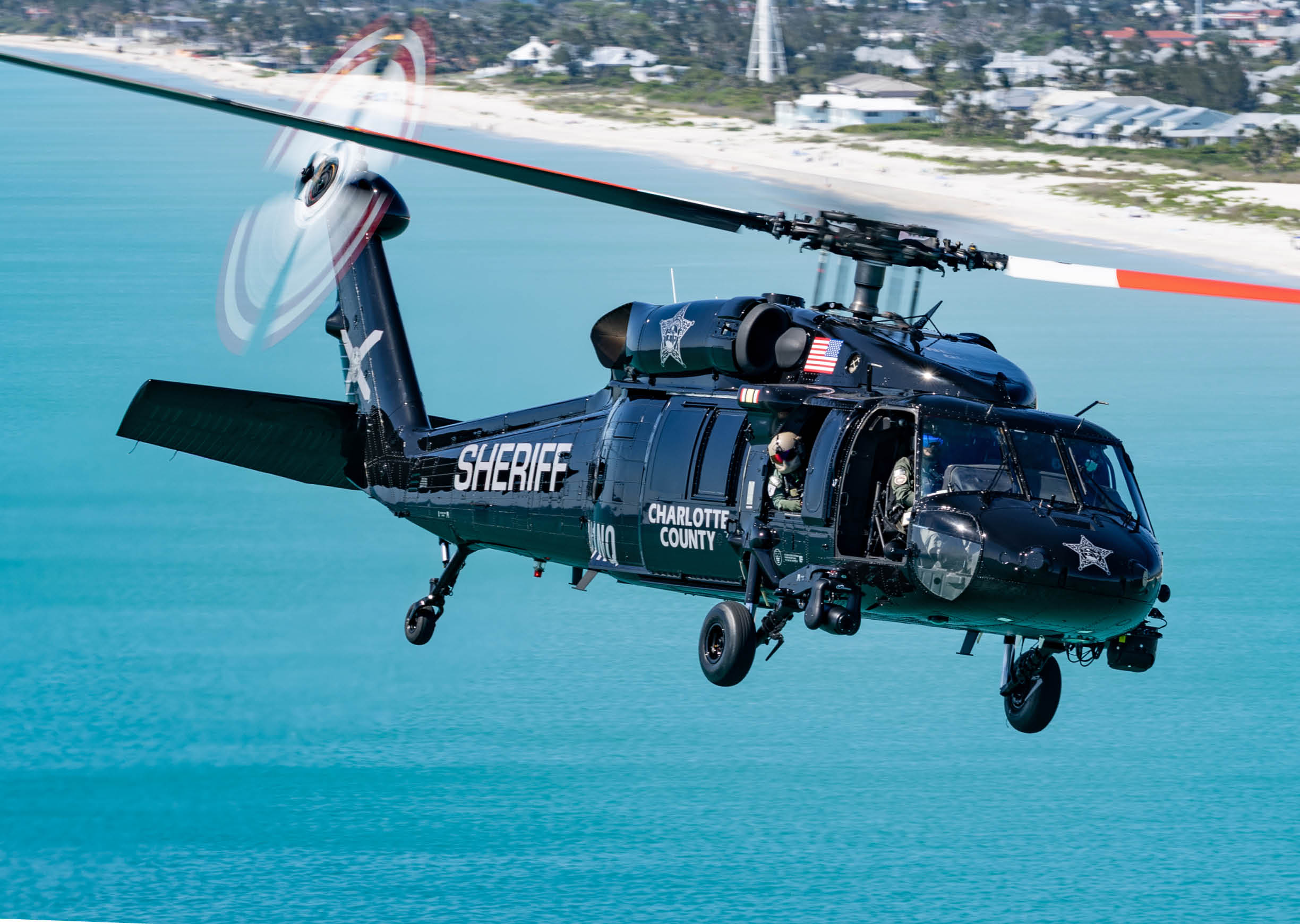 A helicopter flying over a body of water. Description generated by AI