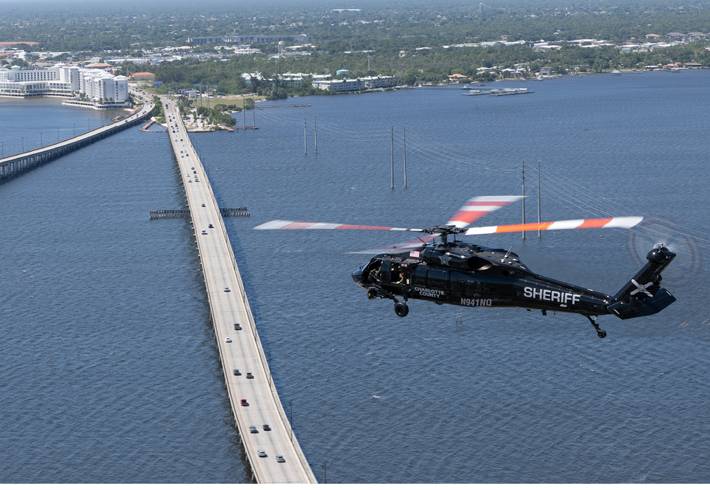 A helicopter flying over a bridge. Description generated by AI