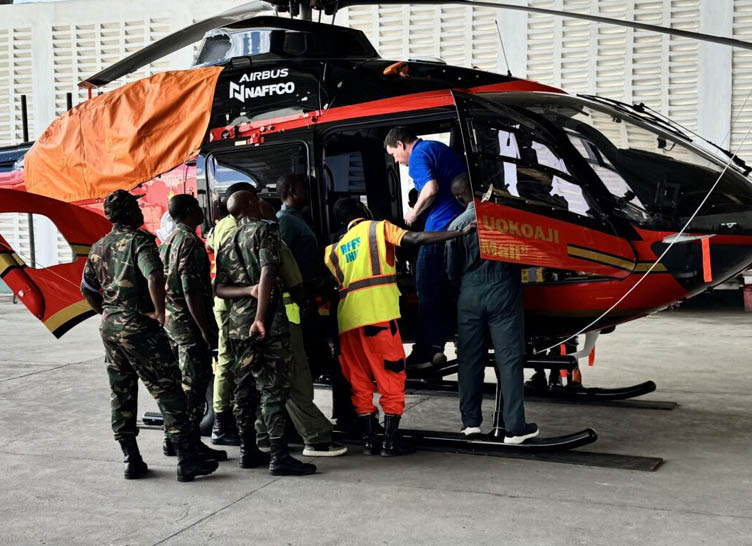 A group of men wearing camouflage uniforms are standing around a helicopter. Description generated by AI