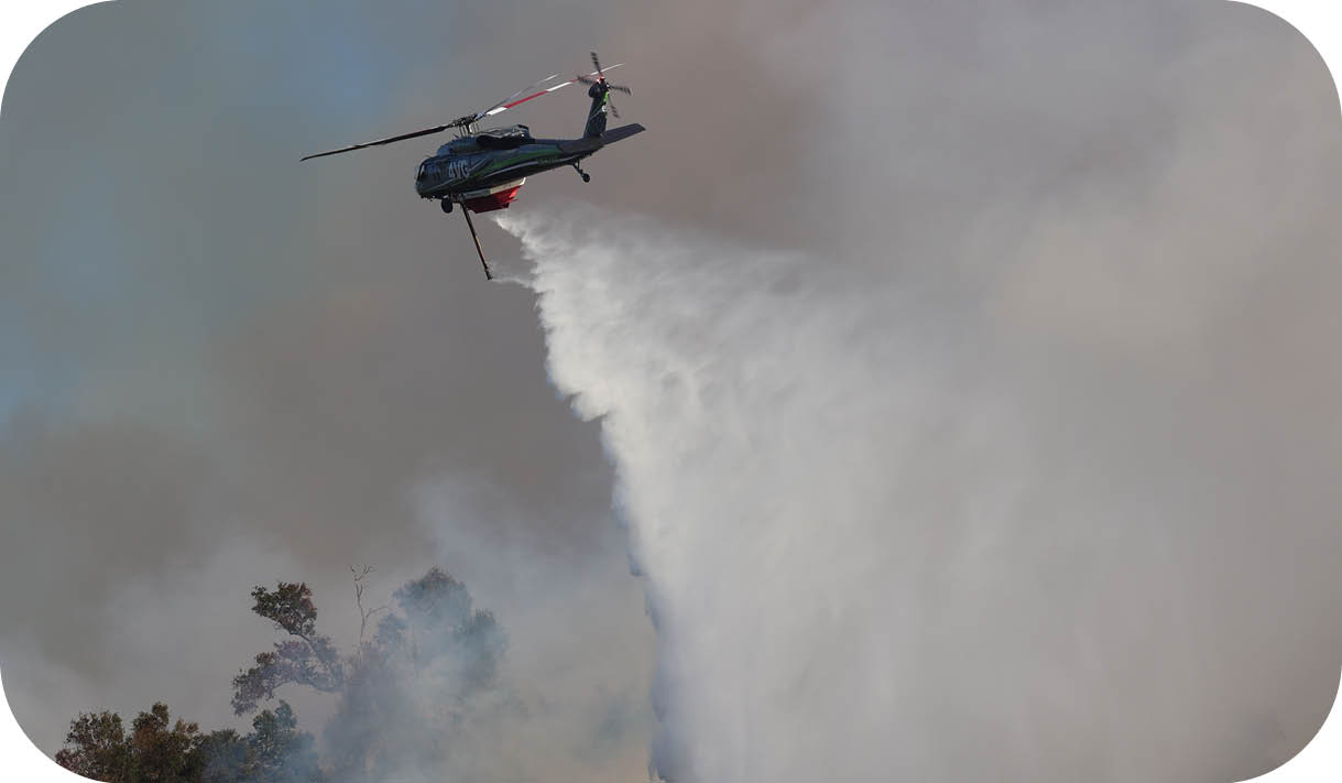 A helicopter is flying over a forest fire. Description generated by AI
