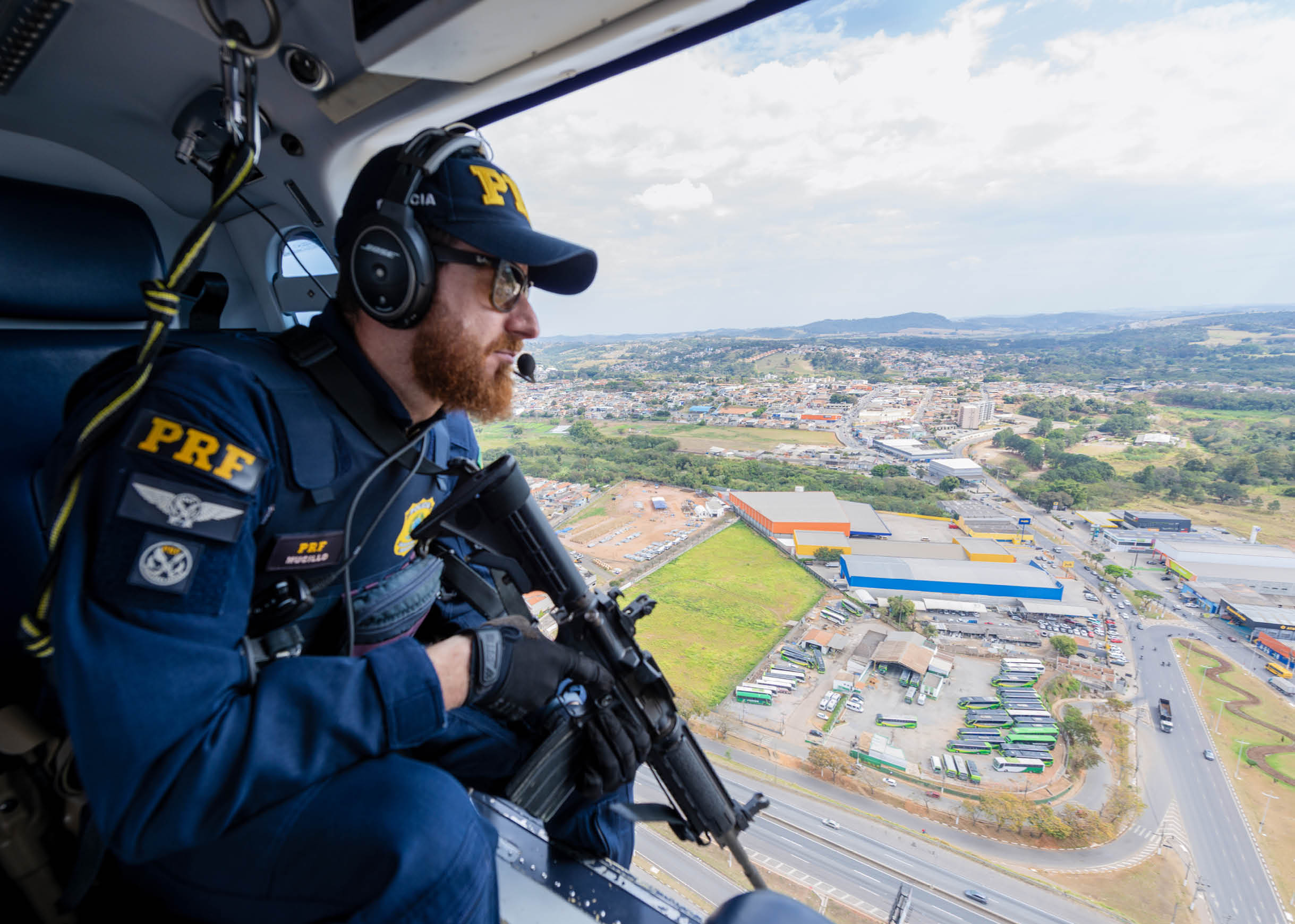 A man wearing a blue uniform and a helmet is sitting in a helicopter. Description generated by AI
