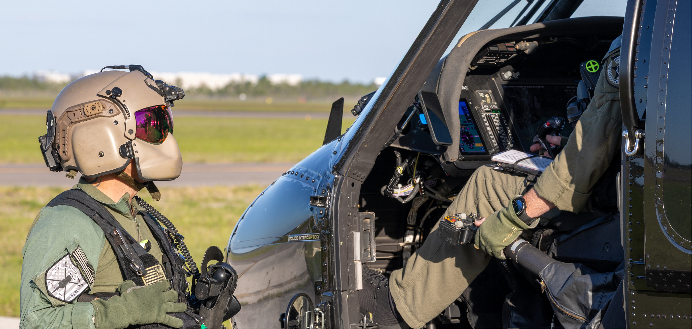 A man in a green uniform is standing next to a helicopter. Description generated by AI