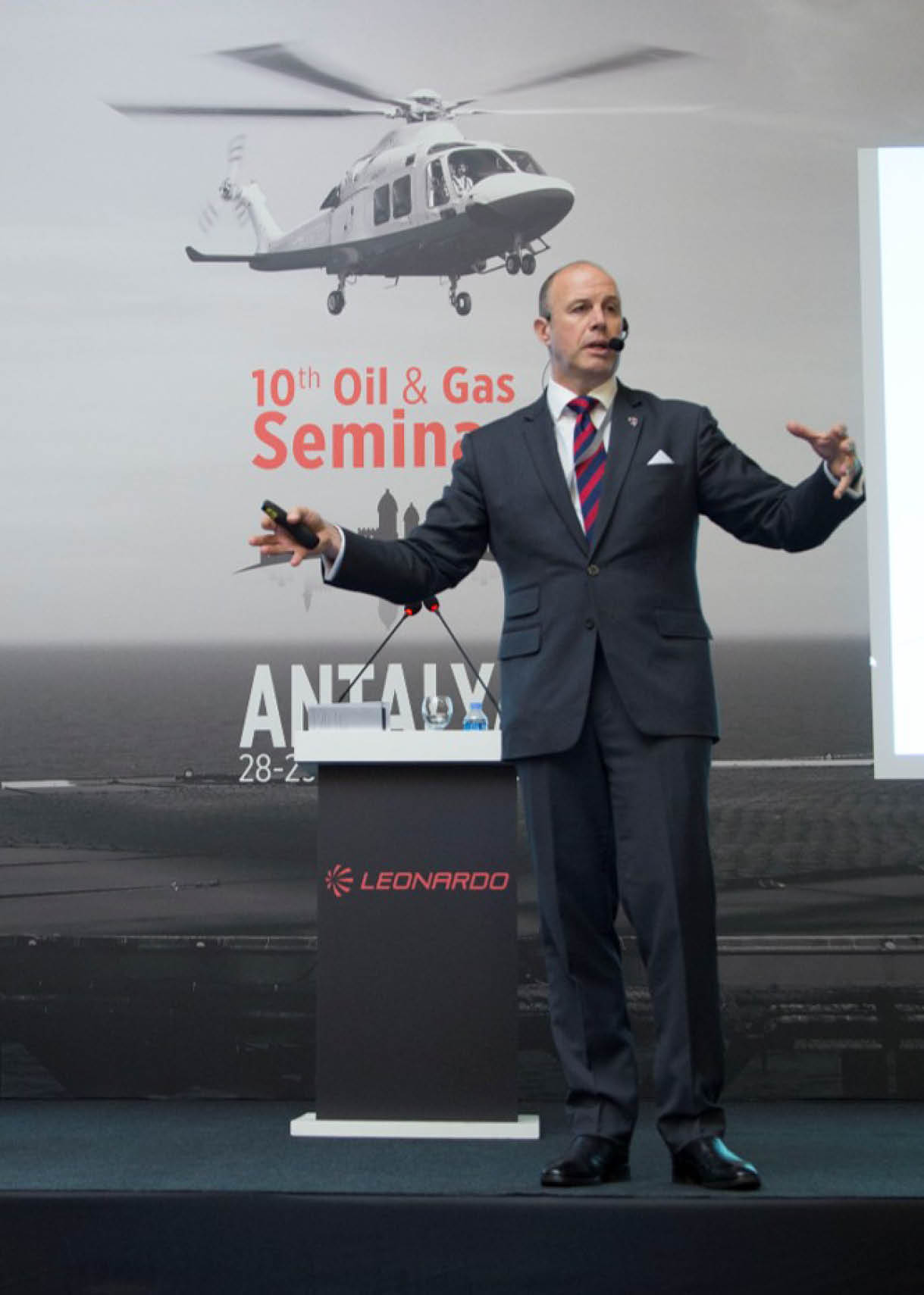 A man in a suit is standing in front of a helicopter. Description generated by AI