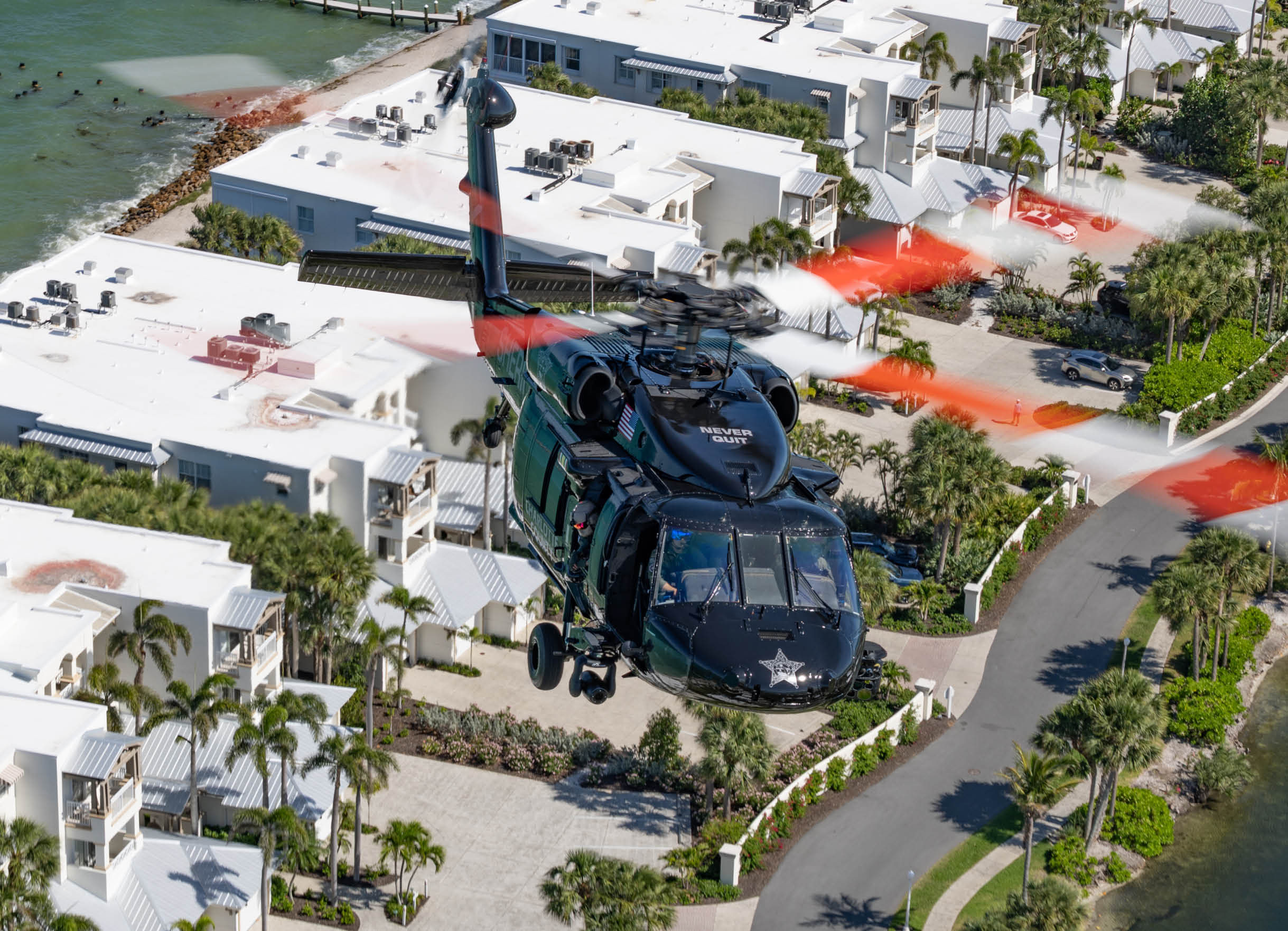 A helicopter is flying over a house with a red roof. Description generated by AI