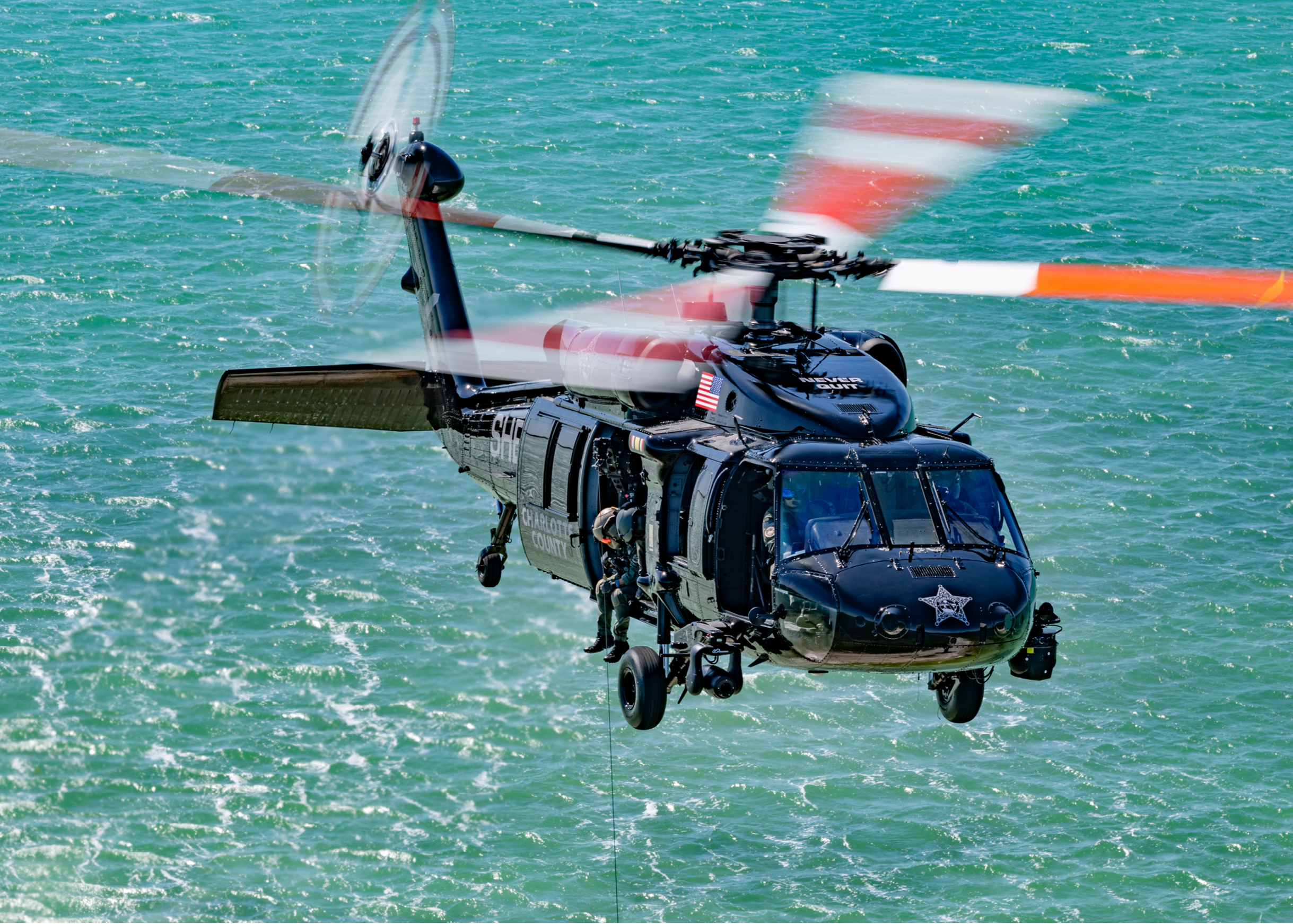 A black helicopter with a red and white tail. Description generated by AI