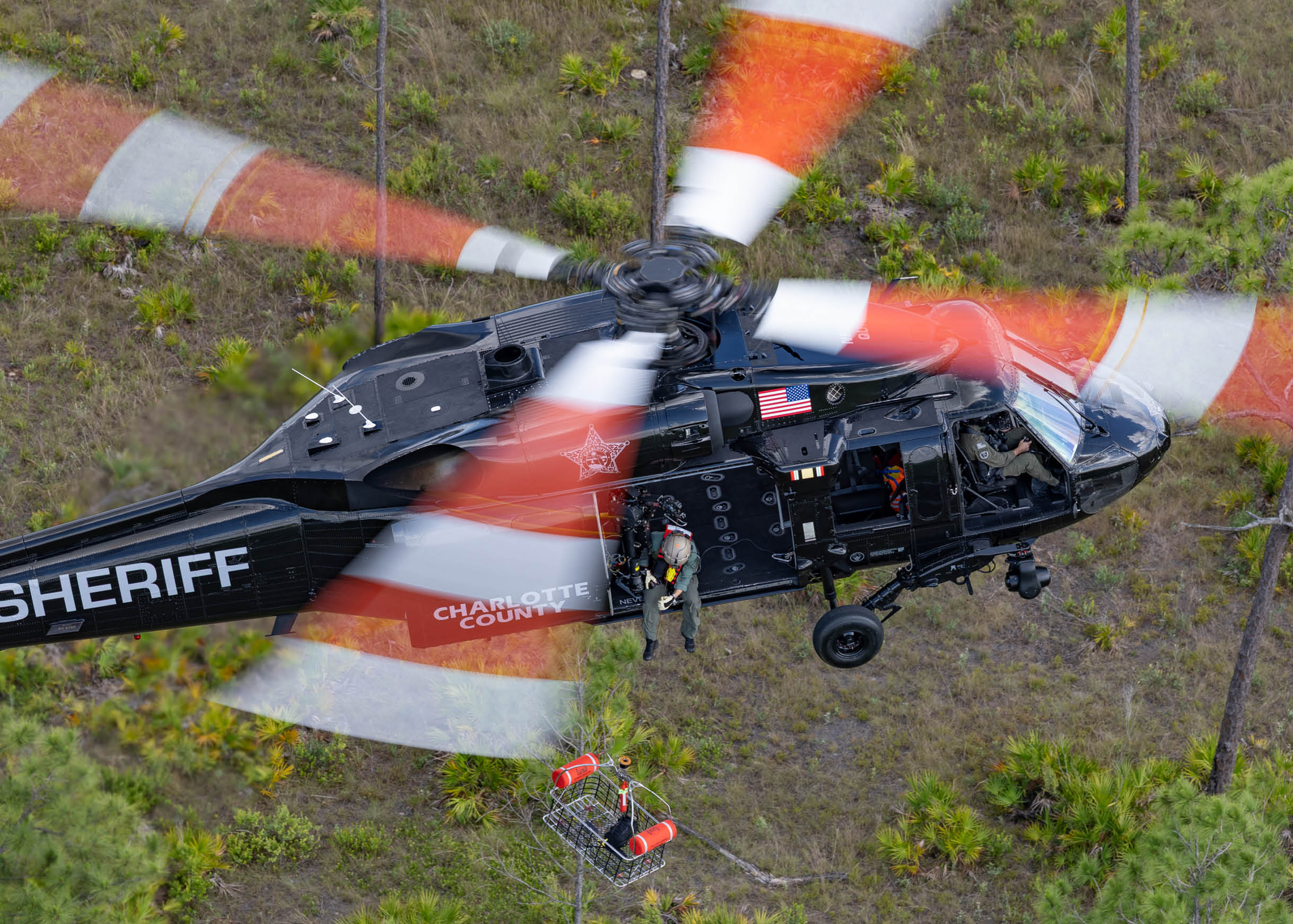 A helicopter with four people on it. Description generated by AI