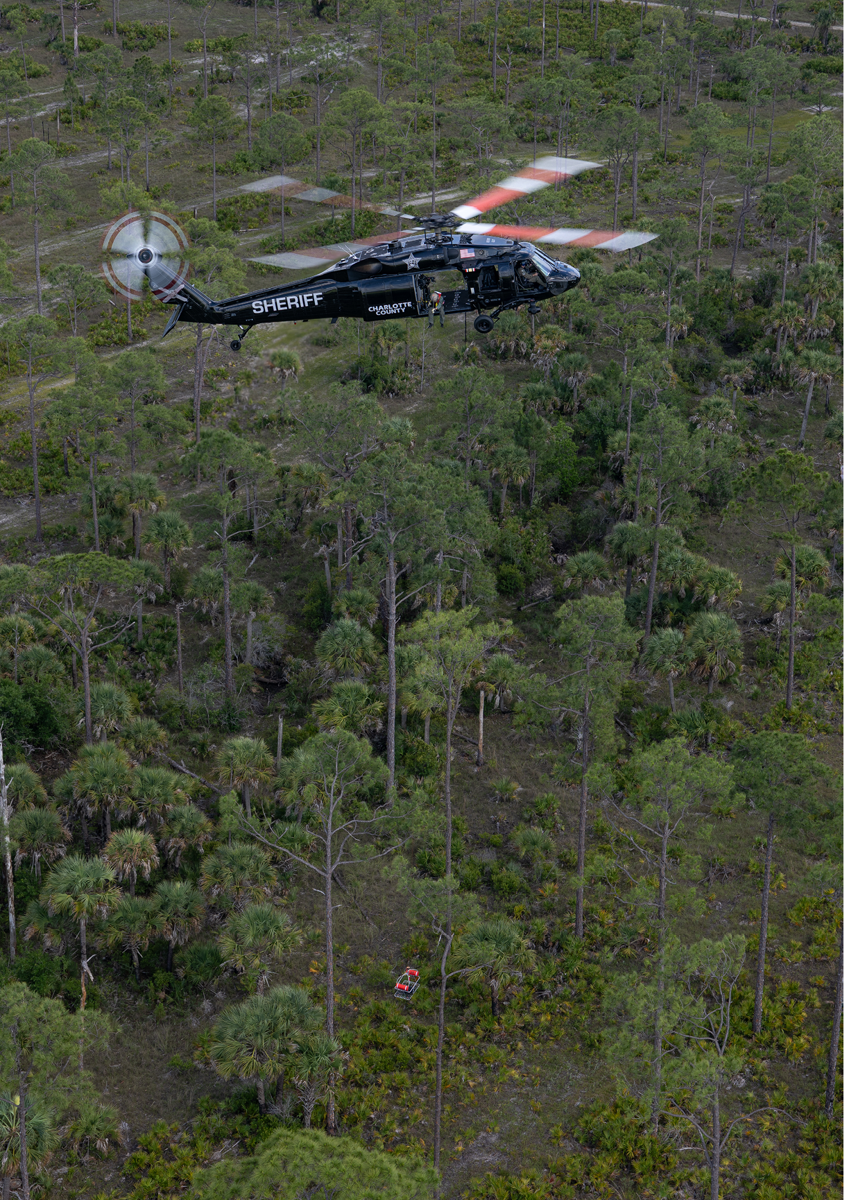 A black helicopter flying over a body of water. Description generated by AI