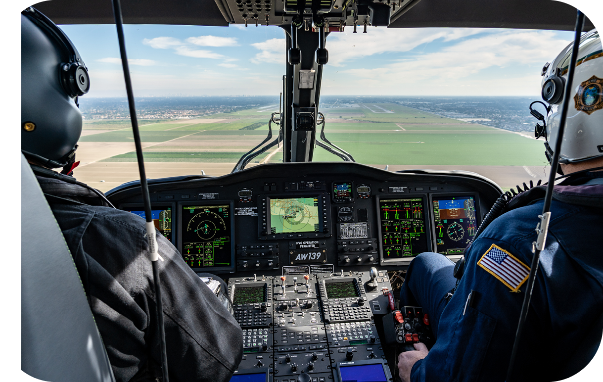 A helicopter flying over a field with windmills in the background. Description generated by AI