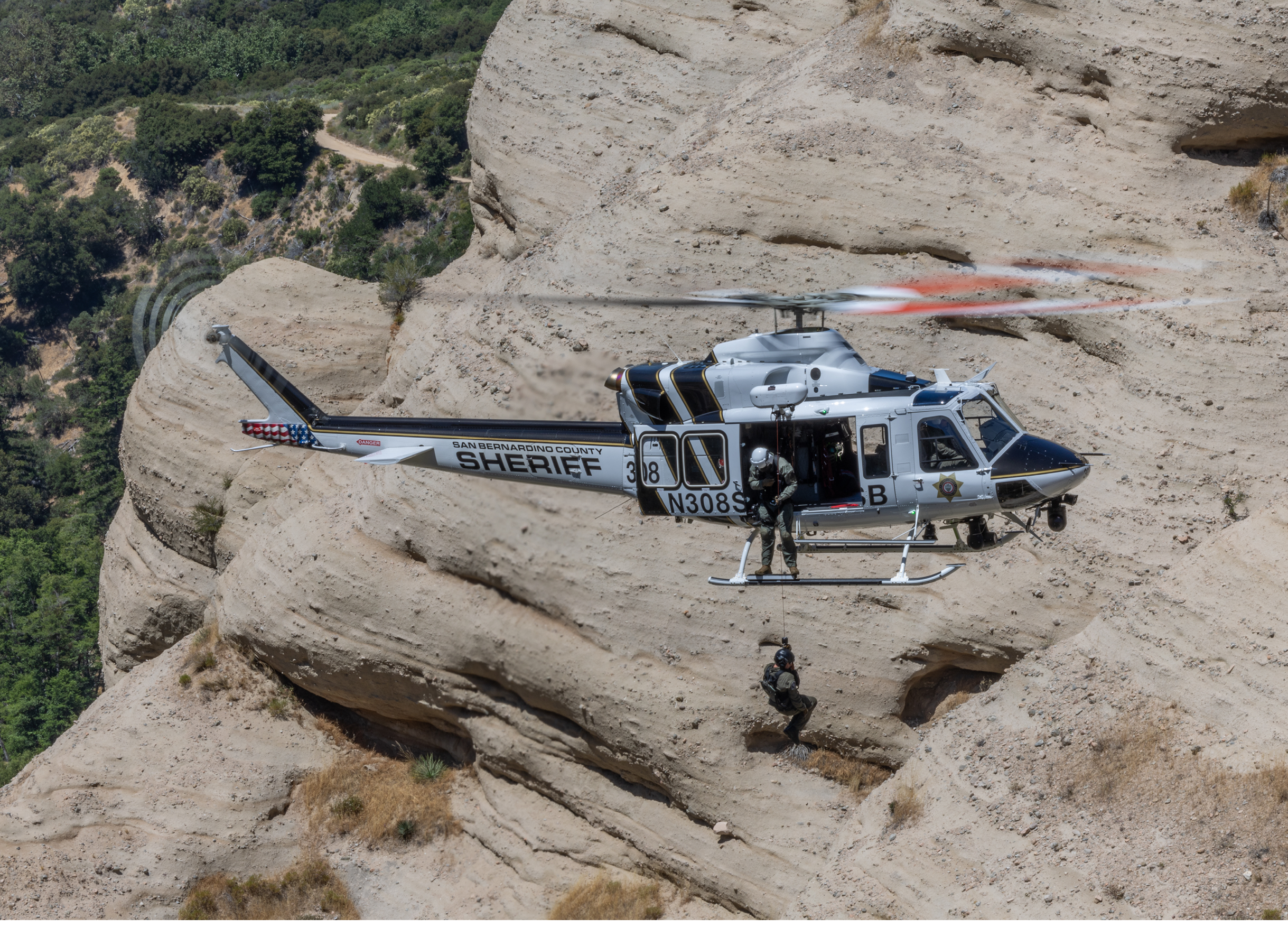 A man wearing an orange shirt is in a helicopter. Description generated by AI