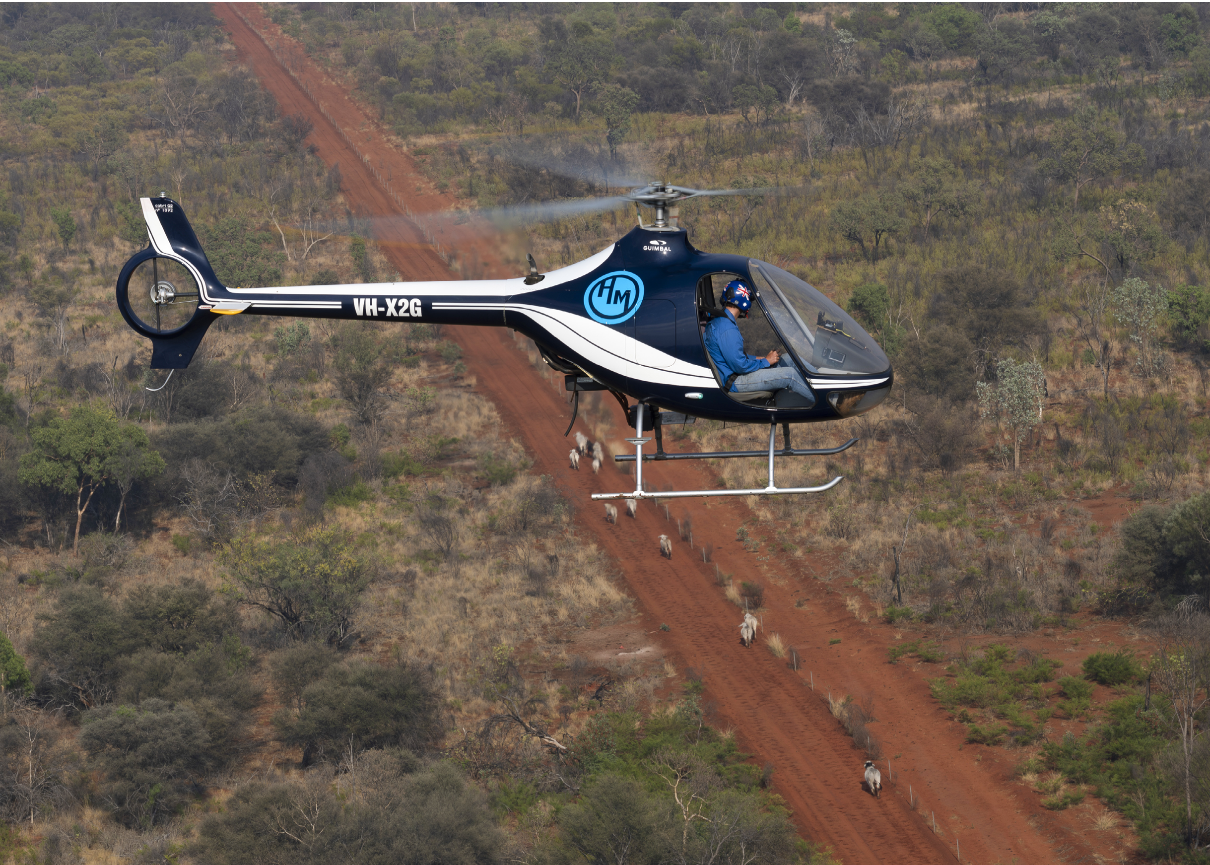 A black helicopter flying over a beach. Description generated by AI