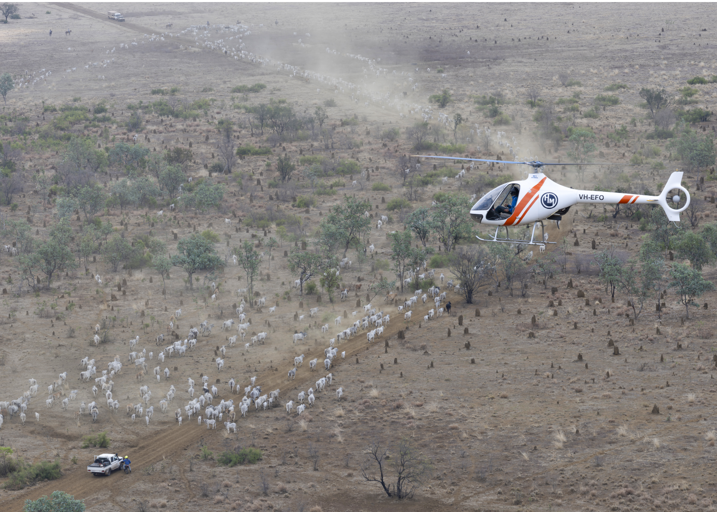 A black helicopter flying over a beach. Description generated by AI