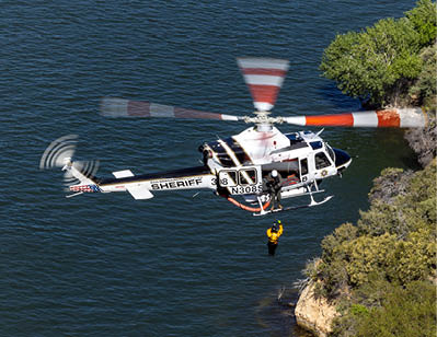 A red and white helicopter flying over a mountain. Description generated by AI
