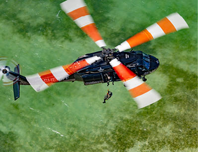 A man wearing a blue shirt and a helmet is sitting in a helicopter. Description generated by AI