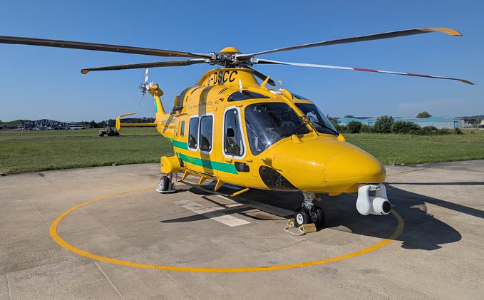 A helicopter with a checkered pattern on it is flying over the ocean. Description generated by AI