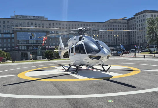 A helicopter with a man in a red jacket on it. Description generated by AI