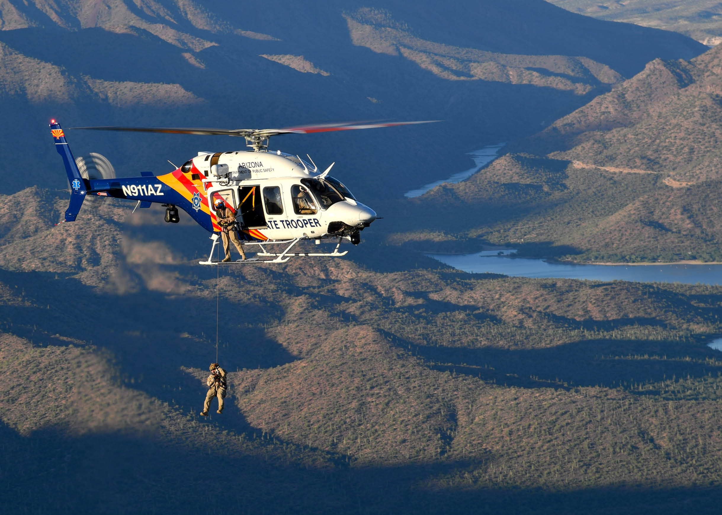 A red and white helicopter flying over a mountain. Description generated by AI