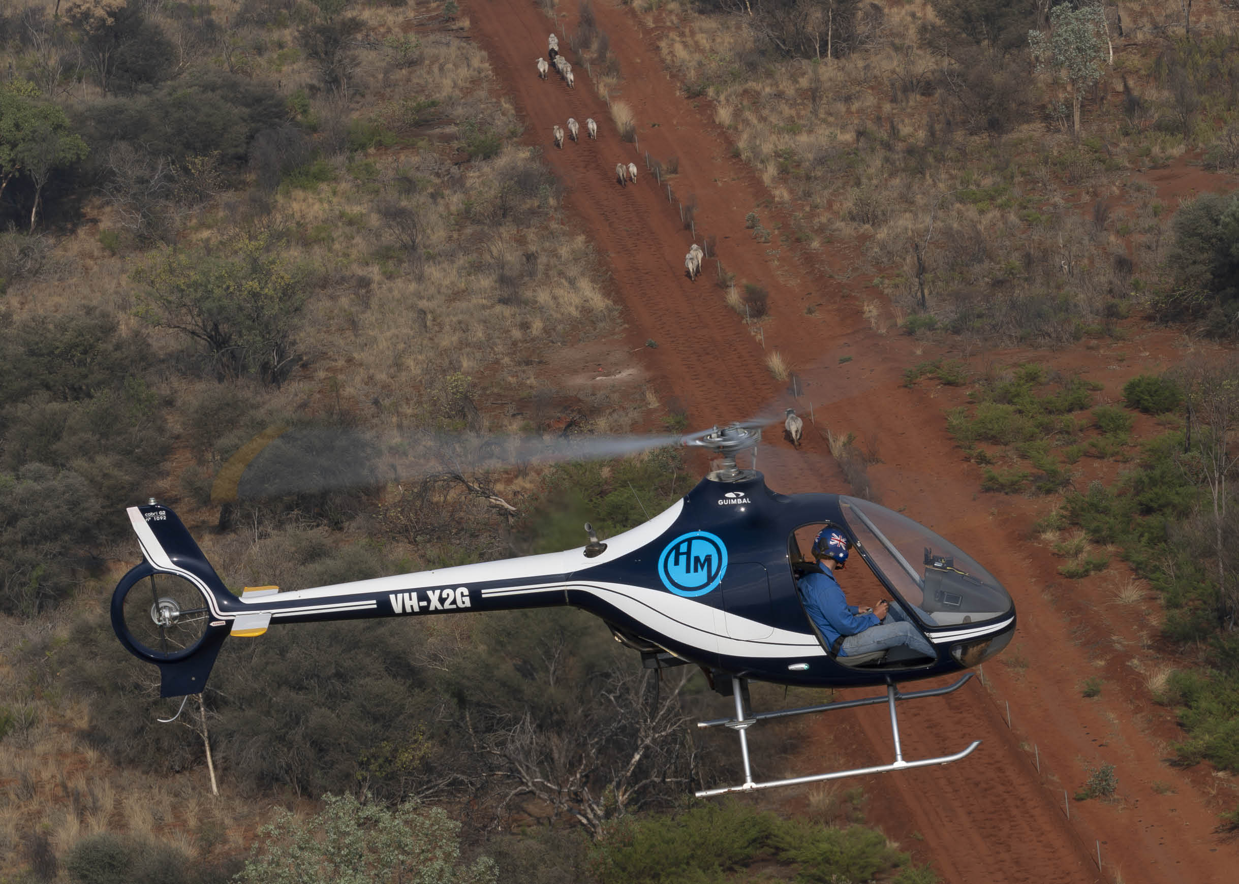 A man wearing a blue uniform and a helmet is sitting in a helicopter. Description generated by AI
