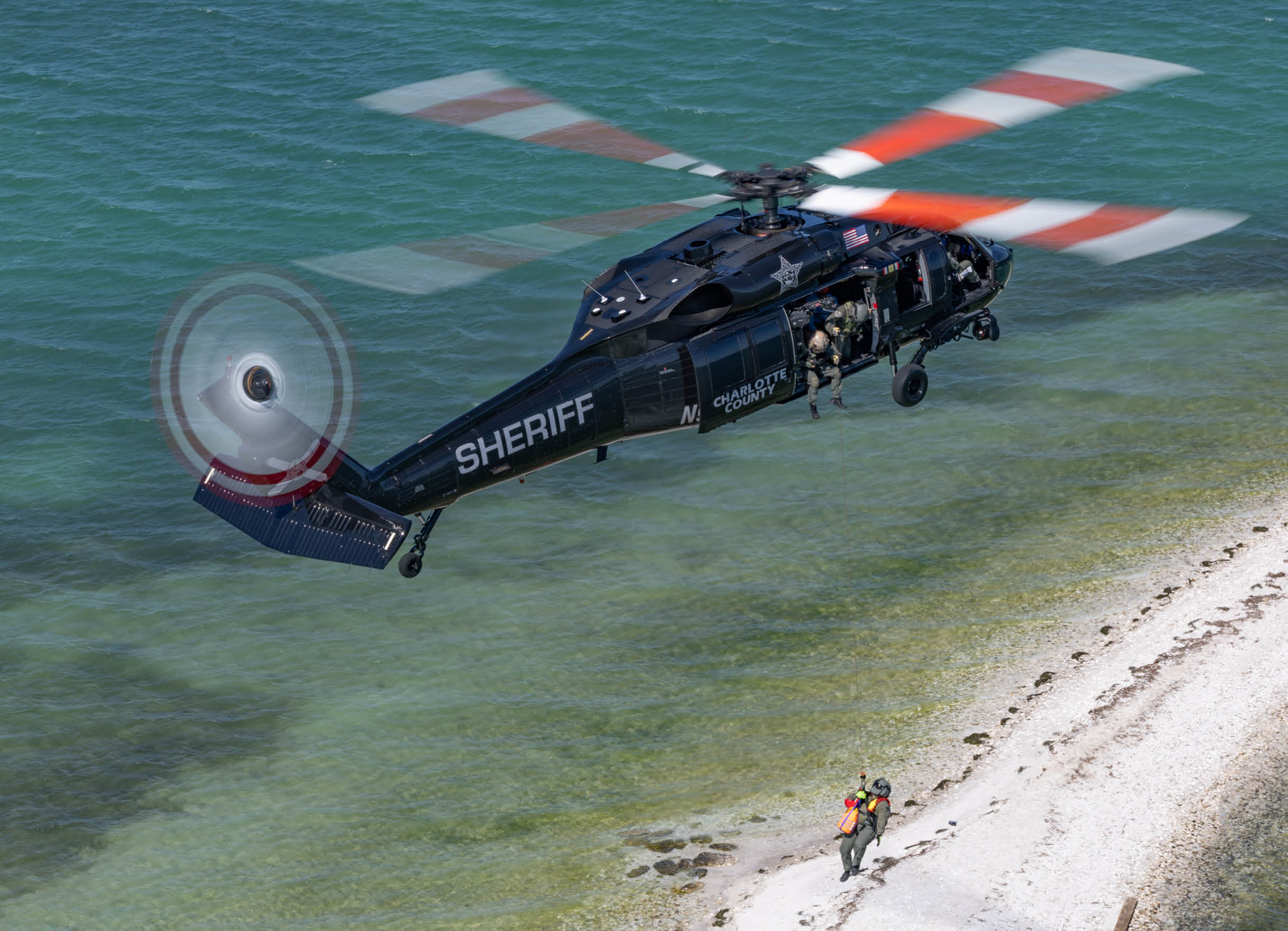 A helicopter is flying over a house with a red roof. Description generated by AI