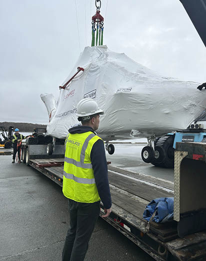 A man in a yellow vest is standing next to a truck with a large package on it. AI generated content