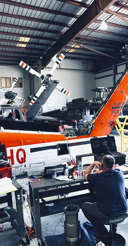 A man is working on a helicopter in a hangar. AI generated content