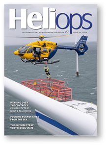 A helicopter hovers above a ship near offshore wind turbines while a person in safety gear is being lowered or lifted by a harness. Description generated by AI