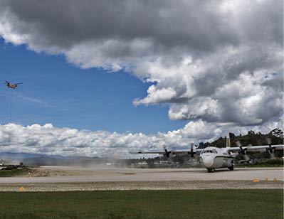 A propeller airplane is landing or taking off on a runway under a partly cloudy sky with dark clouds overhead. Description generated by AI