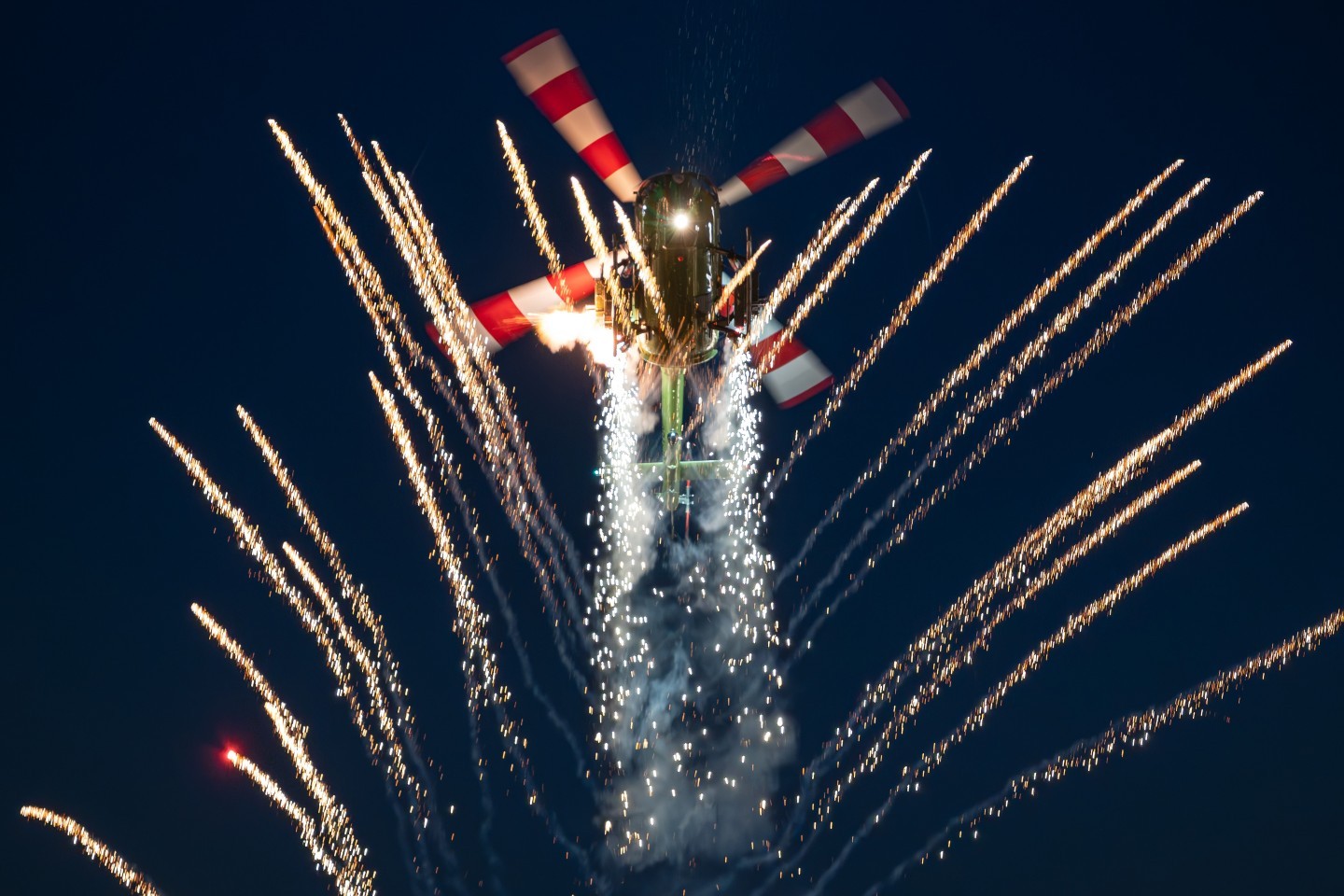 A Messerschmitt-Bölkow-Blohm Bo 105 helicopter shows its maneuverability in combination with fireworls and pyrotechnics during the Sanicole 2025 sunset airshow.