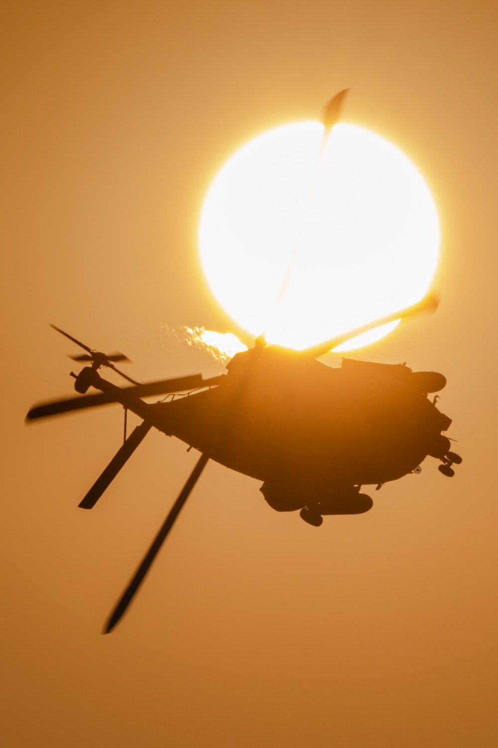 A NH90 TTH helicopter of the German Army flies into the sunlight at the Antidotum 2025 airshiw in Poland. The German Army NH90 Display Team is a helicopter display team of the German Army Aviation Corps. Operating under the Tactical Helicopter Regiment 10 (TrspHubschrRgt 10) based in Faßberg, the team showcases the advanced capabilities and versatility of the NH90 helicopter, representing the prowess of the German Army in aerial demonstrations.