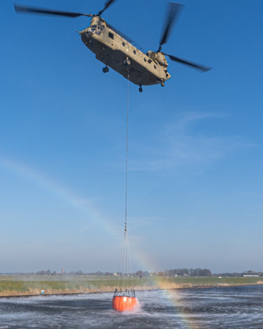 Here you see a Dutch CH47F Chinook practicing with the Bambi Bucket. It was a beautiful, clear day. At just the right moment, a rainbow appeared. That's a striking detail in the photo.