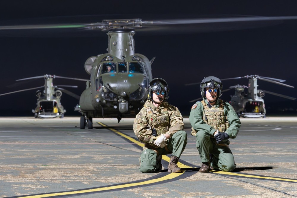 Pilots from the No. 27 Squadron of the British Royal Air Force posing in front of their Boeing Chinook HC6 military helicopter during a night shoot at RAF Odiham, UK.