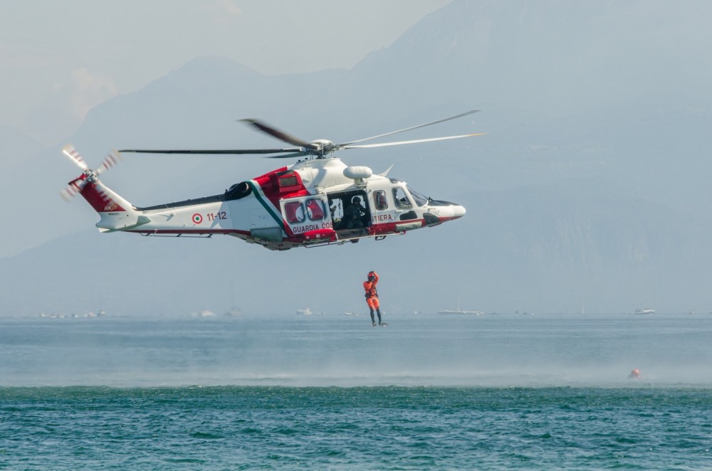 Leonardo AW139 "Coast Guard" callsign "Nemo" engaged in demonstration activities, as the air rescuer launches to recover a shipwreck victim in Lake Garda, in front of the castle of Sirmione del Garda.