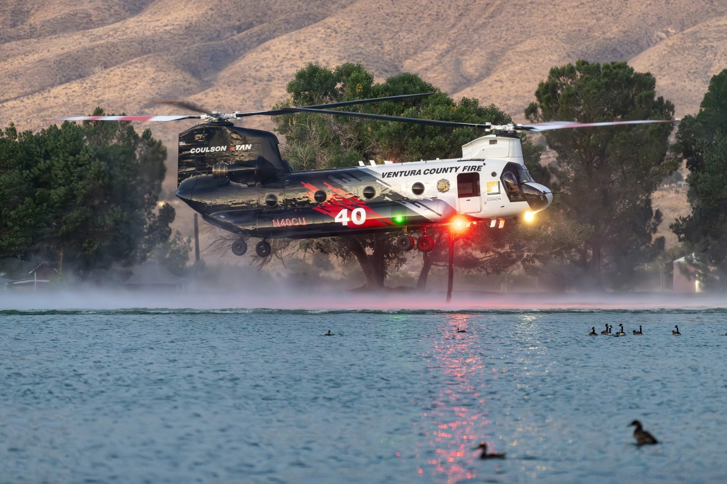 This photograph was actually taken at night - 8:18 in early June.  I used my Nikon 70mm to 200mm f/2.8, at 200mm, and with a setting of1/200th of a second at f/2.8. I used an ISO of 6400 and with Photoshop's Denoise in Camera Raw, it eliminated all the noise.  I was amazed at the quality of the image. The ducks in the photograph really add to the uniqueness and photo illustrative quality. Coulson's Chinook was picking up water at Hesperia Lake Park for the Ranch Fire.