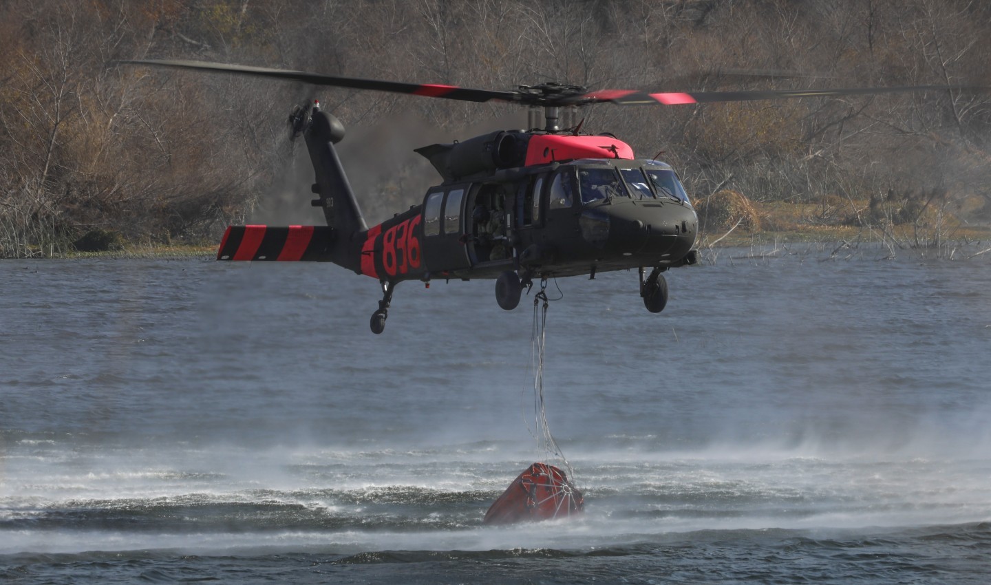 GUARD836 (operated by the California National Guard), scooping up water with a bambi bucket, during firefighting operations on the 6,000+ acre Border 2 Fire in San Diego County, California, early 2025.