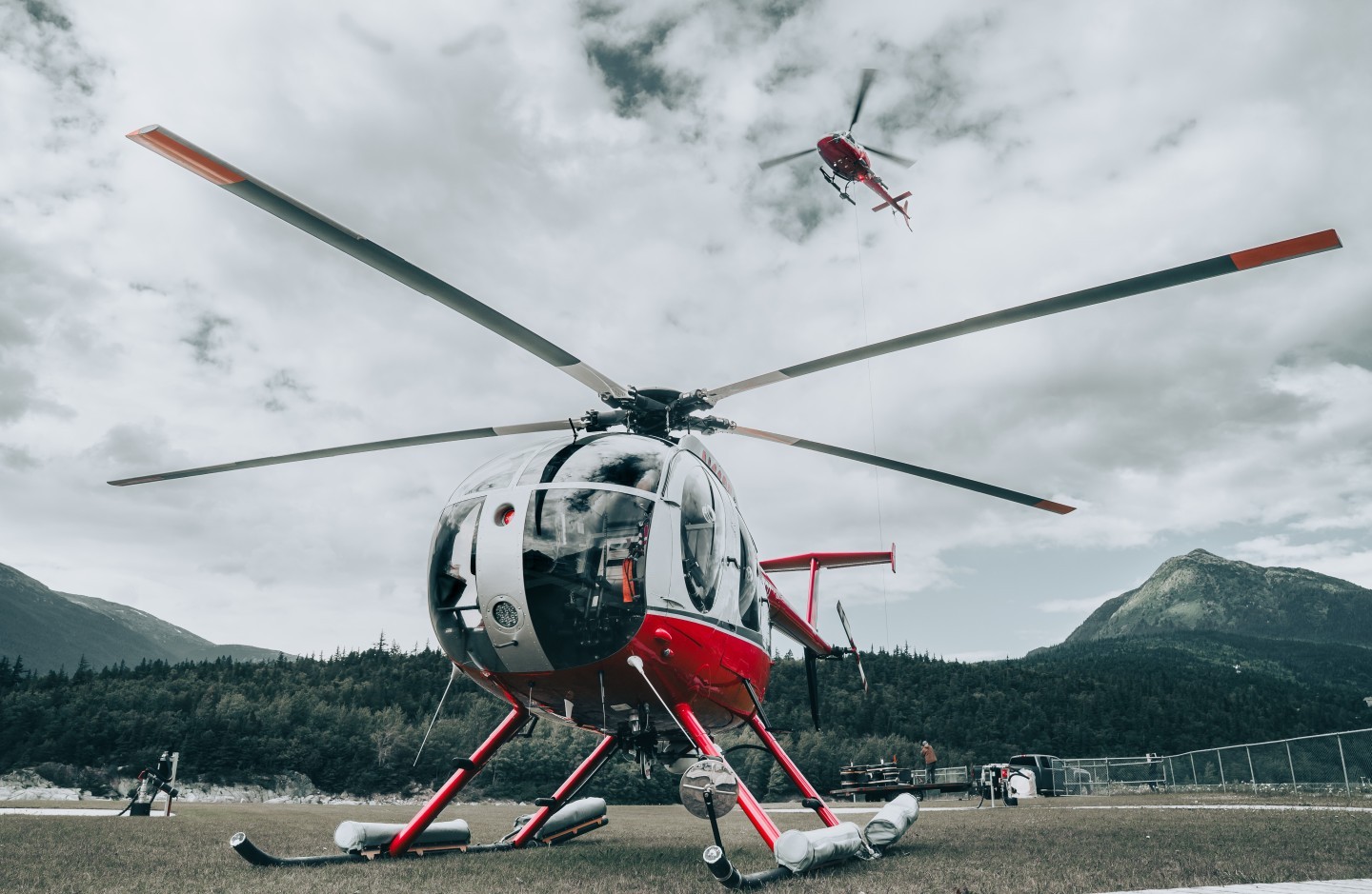 A TEMSCO MD500D sits and waits in the grass while an Astar is running sling loads down from the nearby glacier.