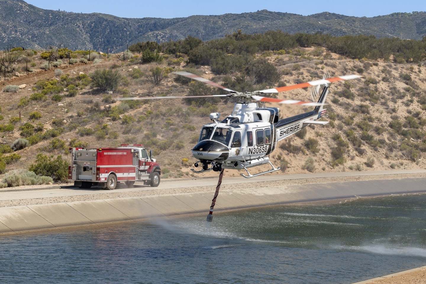 San Bernardino Sheriff's "Fire Attack" Bell 412 helicopter lifts off after picking up water in the California Aqueduct to put on a prescribed burn near Silverwood Lake. I hiked up a hill opposite the aqueduct so that I could be above or at eye level as I photographed.